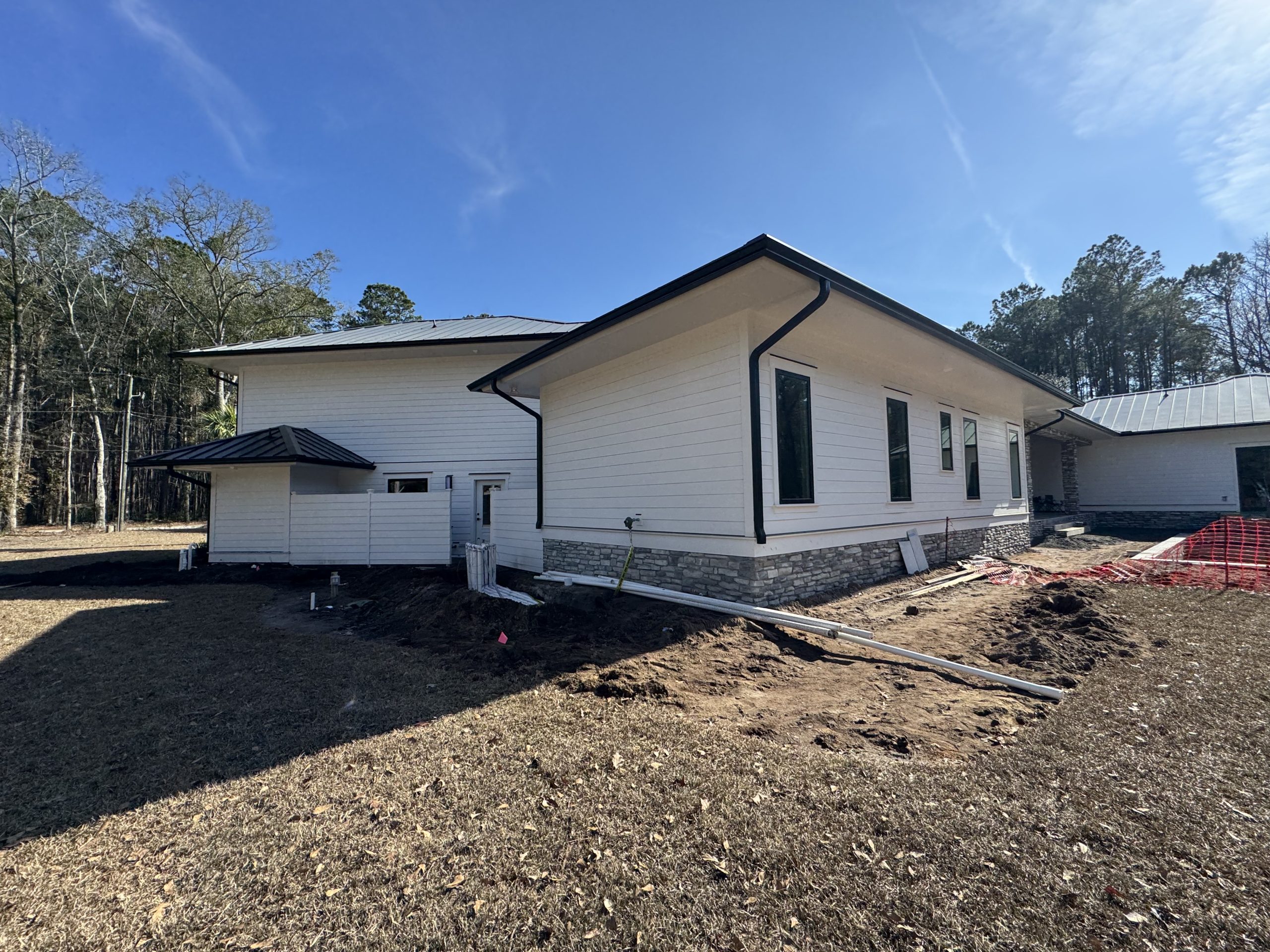 White house under construction with black gutter system and downspouts installed to manage roof drainage